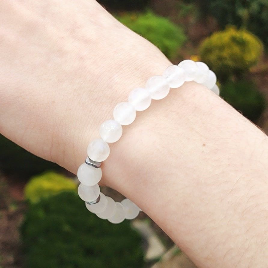Handmade natural white Moonstone beaded bracelet with silver spacers on a wrist, capturing the stone's milky translucence and soft sheen against a natural background.