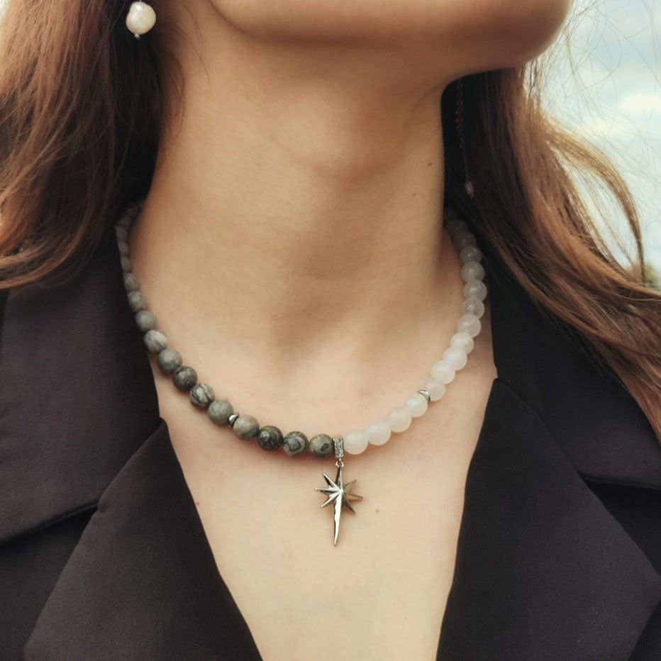 Unique half-and-half beaded necklace design featuring grey Jasper and translucent white Moonstone beads meets at a silver North Star pendant.