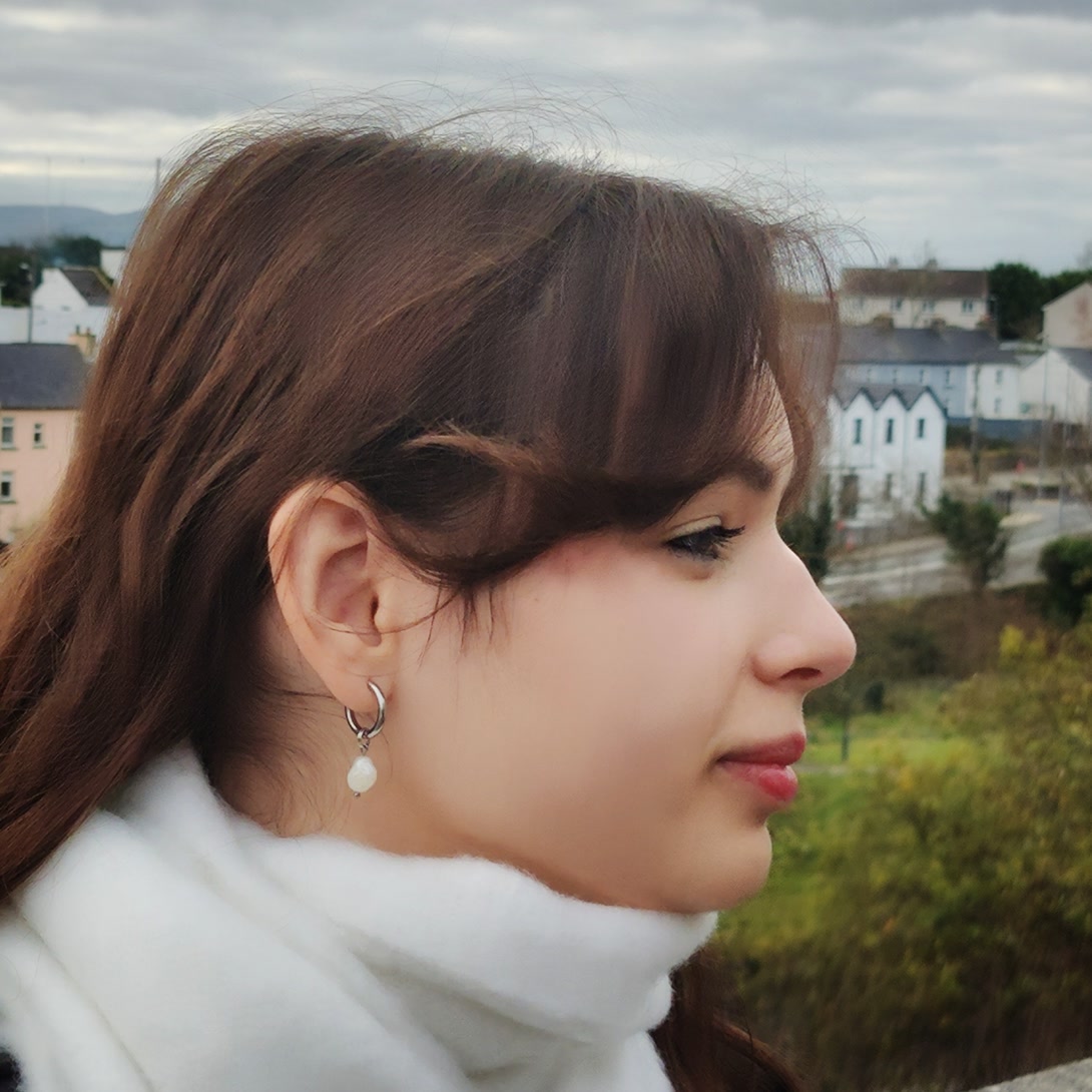Profile view of a woman wearing a delicate silver hoop earring with a single natural white Pearl drop charm.